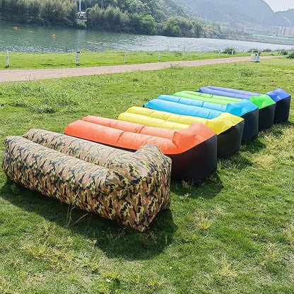 Multiple Relax™ Inflatable Sofa Beds in various colors lined up on a grassy field. Lightweight and easy to inflate, perfect for outdoor relaxation.