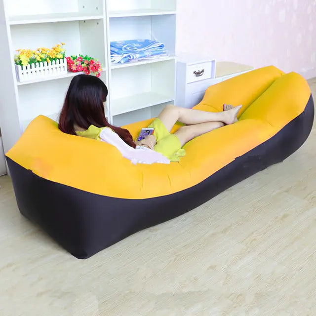 Yellow and black Relax™ Inflatable Sofa Bed with a woman relaxing indoors. Comfortable and easy to inflate, ideal for various settings.