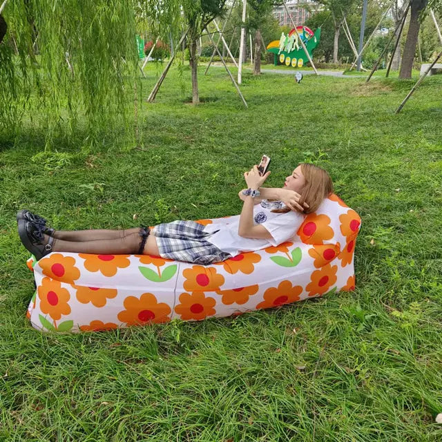 Floral-patterned Relax™ Inflatable Sofa Bed with a woman lounging outdoors. Stylish and portable, perfect for picnics and camping trips.