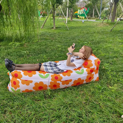 Floral-patterned Relax™ Inflatable Sofa Bed with a woman lounging outdoors. Stylish and portable, perfect for picnics and camping trips.