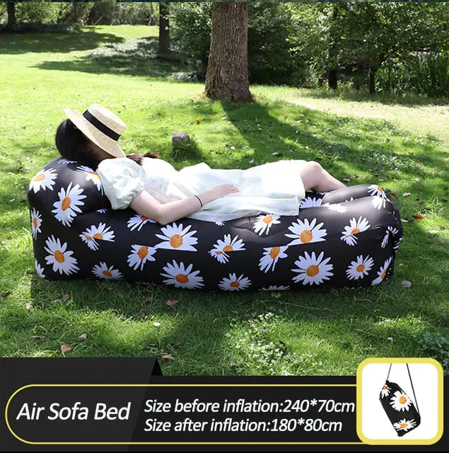 Black Relax™ Inflatable Sofa Bed with daisy print, used outdoors. Lightweight and stylish, perfect for camping and picnics.