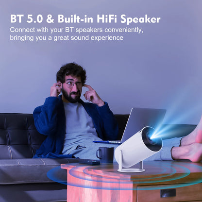 Movieclub™ Ultra HD home/outdoor projector with BT 5.0 and built-in HiFi speaker, projecting a bright image while a man enjoys immersive sound.